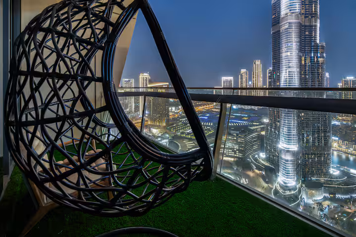 Burj Vista: The hanging chair on the balcony at night, the Burj Khalifa lit behind it
