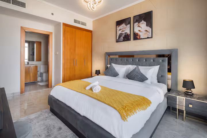 The Links East: The bedroom, a king bed with a grey headboard and a yellow throw