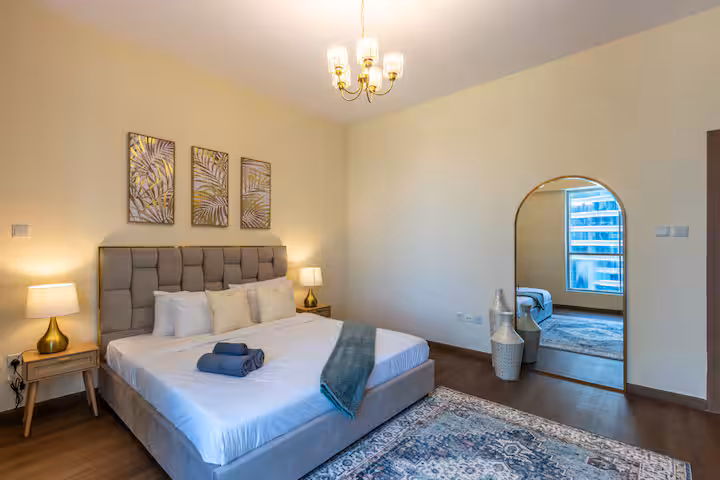 Sulafa Tower: Bedroom one, a king bed, a blue rug, the towers in the window