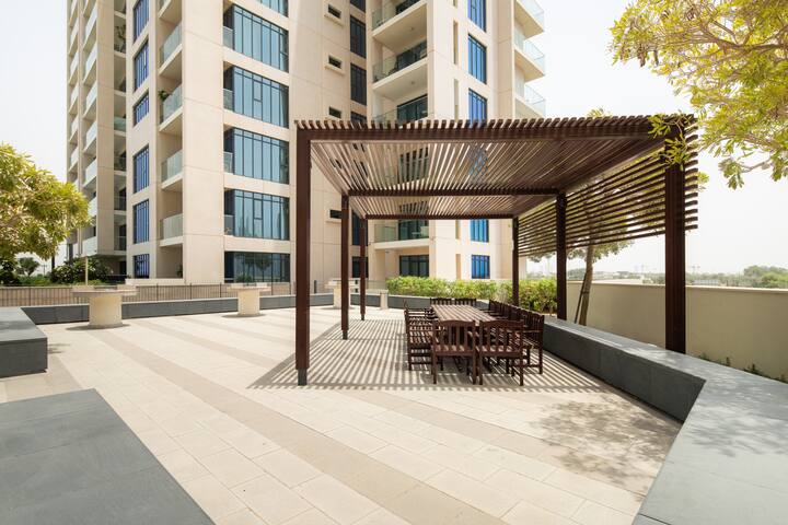 Vida Residences, The Hills: the patio of a holiday home with a table and chairs, the garden beyond